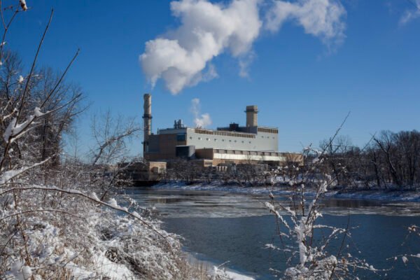 Industrial plant emitting steam over a snowy river
