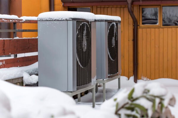 Two residential modern heat pumps buried in snow