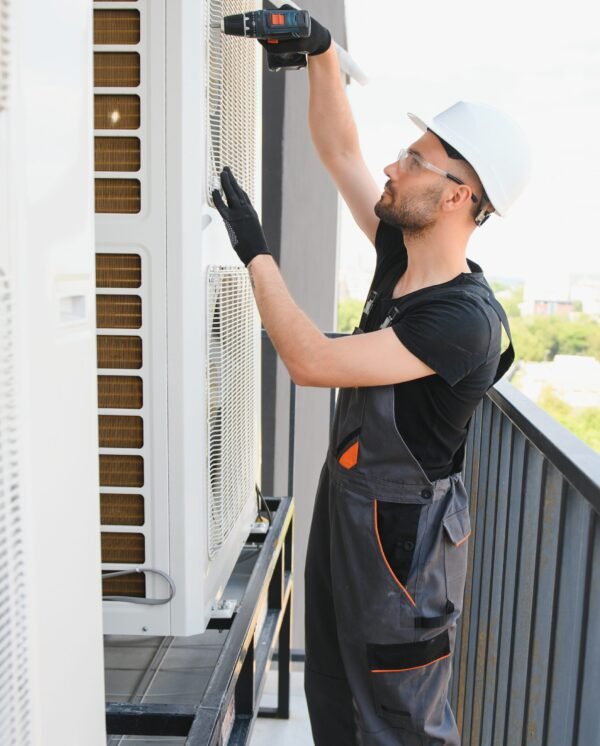 technician working on air conditioning or heat pump outdoor unit. HVAC service, maintenance and repair.